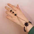 Détail de la gourmette fleurie dorée avec pétales en pierres noires sur modèle - Style Pendentif Fleur Chaîne Double Couche Or (1087)