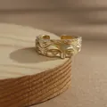 Gros plan d'une bague dorée avec relief visage de Vénus sur socle en bois - Or