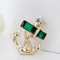 Golden anchor brooch with emerald green crystals and nautical rope design on white background - Green