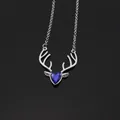Macro shot of silver deer head pendant with deep blue teardrop gemstone on black background - Silver and Royal Blue