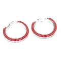 Gros plan de boucles d'oreilles créoles argentées ornées de trois rangs de strass rouges - Rouge