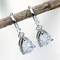 Detailed view of silver pear-cut crystal leverback earrings hanging on a natural branch - White