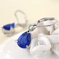 Detailed macro view of pear-cut dark blue crystal drop earrings with silver leverback hooks - Blue