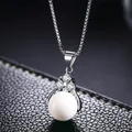 Vista macro de collar de cadena box plateada con colgante de esfera blanca y tres circones - Concha Blanca