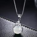 Close-up of a silver box chain necklace with a milky opal pendant and zircon accents - Agate