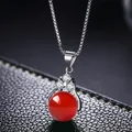 Macro shot of a red round gemstone pendant with white zircon stones on a silver box chain - Red Agate