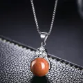 Detalle macro de un collar de plata con un colgante brillante de piedra de arena marrón - Piedra de Arena Dorada