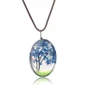 Détail du pendentif ovale en résine avec fleurs séchées bleues et petit papillon - Bleu foncé