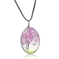 Gros plan du pendentif ovale en résine avec fleurs séchées violettes et papillon - Rose rouge