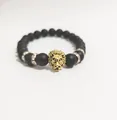 Detalle de cuentas negras mates y cabeza de león dorada en una pulsera de lujo para hombre - Oro antiguo