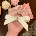 Detalle de pinzas de lazo crema y rosa con diamantes de imitación en forma de corazón - crema