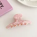 Dettaglio di un grande fermaglio per capelli in acetato marmorizzato rosa su scrivania - Rosa Fiori di Ciliegio (Stile Dritto)