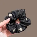 Detail of black mesh scrunchie with 3D white rose buds showing fluffy pleated texture - Black