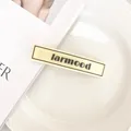 Détail d'une pince à cheveux crème minimaliste avec texte larmood sur fond de céramique - Pince à Bec de Canard Jaune Rectangulaire