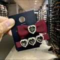 Détail de barrettes à nœud rouge vin avec des strass en forme de cœur noir et des cristaux - Ensemble de Pinces à Cheveux Cœur / Rouge