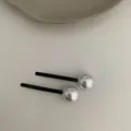 Detail view of two minimalist black alloy hair pins with reflective silver metal spheres - Silver Ball Style