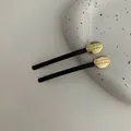 Pair of black hair clips with gold oval discs featuring Believe in Yourself engraving - Gold Oval Style
