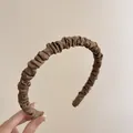 Dettaglio del cerchietto in raso plissettato marrone con trama setosa e design voluminoso - Bordo Sottile Plissettato / caffè