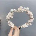 Detail van een geplooide satijnen haarband in beige met elegante witte parels - Broken Wit