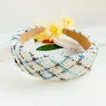 Close-up of a wide tweed headband with blue and gold weave and soft suede lining - White Grid