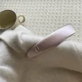 Detailed close-up of a pale pink satin headband with a golden oval metal emblem detail - Light Pink