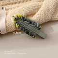 Detail shot of a 6.8cm handmade knit hair clip with olive green metal and colorful yarn - Gray
