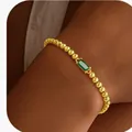 Élégant bracelet à perles dorées avec zircon vert rectangulaire au poignet d'une femme - 14k / Or Mai (Vert)