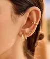 Détail de boucles d'oreilles papillon dorées et créoles en cristal portées à l'oreille - Style Nœud Minimaliste et Créole avec Pierre (e1775)