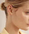 Gros plan de boucles d'oreilles papillon dorées minimalistes portées sur l'oreille de femme - Style Cœur et Barre en Pavé de Zirconium (e1771)