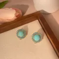 Macro detail of turquoise stud earrings with gold plating and vintage sunflower design - Round Style (e005)