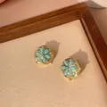 Macro detail of vintage gold-plated turquoise flower earrings on a beige linen tray - Six-Petal Flower Drop (e005)