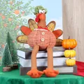 Thanksgiving turkey plush with pumpkin body, long legs, and green knit hat on a book stack - Orange Female Turkey (CX25508)