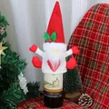 Knitted Christmas wine bottle cover featuring a red gnome with a white beard and holly berry - Red Heart Hat Style