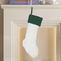 Witte kabelgebreide kerstsok met groene boord hangend aan een open haard schouw - Witte Gebreide Kous met Groene Bovenkant