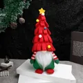 Christmas gnome plush with red tree hat, green body and white beard on a white pedestal - Red Christmas Tree Hat Sitting Gnome