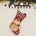 Christmas stocking with 3D Santa Claus and plaid details hanging on a festive wooden wall - Santa Claus