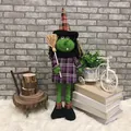 Poupée sorcière d'Halloween avec visage vert et robe violette sur tapis blanc - Sorcière