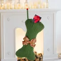 Green knitted dog bone Christmas stocking with red polka dot bow on white fireplace - Green