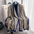 Scialle paisley verde oliva con frange su gruccia vicino a un divano bianco - 185cm / Blu