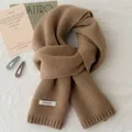 Detail of dark coffee wool scarf with 100% wool label and ribbed knit texture - Camel