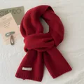 Close-up of 100% pure wool scarf showing soft knit texture and stitched wool label - Red