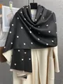 Dettaglio sciarpa nera a pois con cuori e frange sottili su un cappotto bianco - Nero