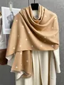 Dettaglio macro della sciarpa in cashmere cammello con cuori bianchi e bordi a frange - Cachi
