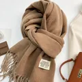 Dettaglio della sciarpa di cashmere cammello con frange ed etichetta su sfondo caldo - 18# Latte