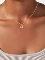 Close-up of golden twisted heart pendant on a delicate water wave chain necklace - Twisted Texture Hollow Heart Necklace (x333) / Gold