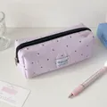 Detail van een lavendelkleurige polkadot etui met metalen rits en minimalistisch label - Paars