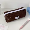 Detail van de donkerbruine pennenzak met polkadots, witte rits en een stoffen label - Bruin