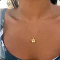 Detalle de un collar con flor de frangipani dorada usado sobre piel con gotas de agua - Estilo Flor de Frangipani (x505) / 14k / Dorado