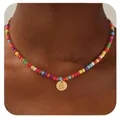 Gros plan de la lettre G gravée sur pendentif doré avec collier de perles colorées - Lettre G