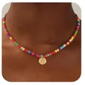 Détail du collier de perles arc-en-ciel avec un pendentif doré rond et la lettre H gravée - Lettre H